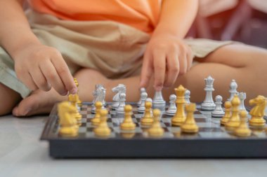 Çocuk satranç taşını aldı ve hamlesini yaptı. Erken gelişim, çocuklar için evde eğitim oyunları. Seçici odak.