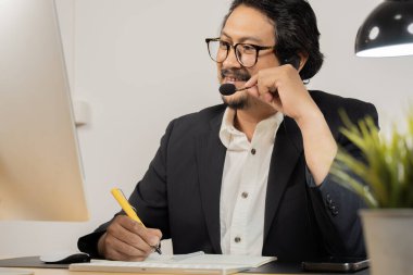 Asyalı erkek çağrı merkezi, müşteri hizmetleri, resmi takım elbiseli teleskoplar, kulaklık takan veya modern ofisteki müşterilerle konuşan kulaklıklar..