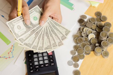 Yakından bakan adamın elinde bir tomar banknot ve yanında bir hesap makinesi olan bir tomar para vardı. Üst görünüm, seçici odak.