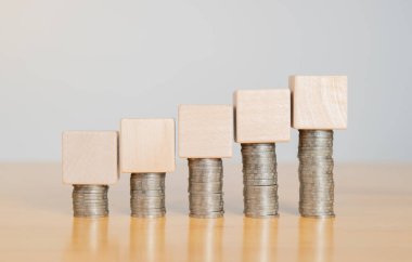 Tahta masadaki madeni para yığınının üzerinde Emtpy ahşap küp. Masrafları ya da maliyet kavramlarını hesapla. Boşluğu kopyala.