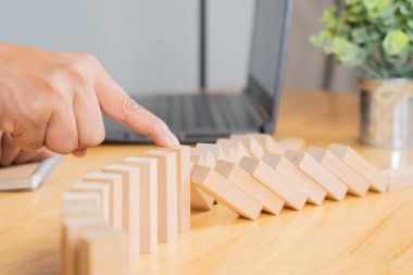 İş adamlarının durması ve tahta masa üzerindeki domino etkisinin korunması riski. Seçici odak.