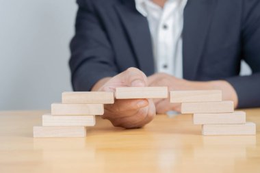 Kimlik değiştiren işadamlarının yakın plan görüntüleri ofiste oturup masa üzerindeki ahşap tuğlalardan oluşan duvarı tamamlıyorlar..
