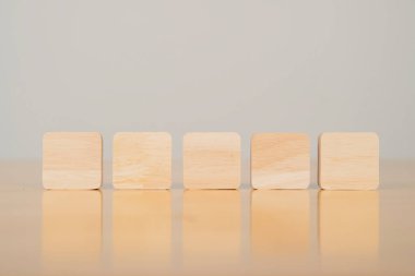 Tahta masa ve beyaz arka planda gölgeli beş tahta kare blok. Boşluğu kopyala.