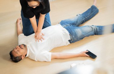 Yetişkin Asain kadın, evde kalp krizi geçiren kocasına kalp masajı yapıyor. Üst Manzara. CPR Konsepti.