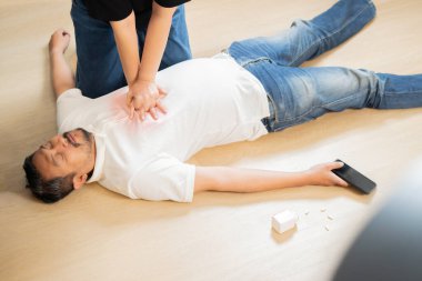 Genç bir kadının evde kalp krizi geçiren kocasına kalp masajı yaparken yüksek açılı görüntüsü. Kalp krizi kavramı.