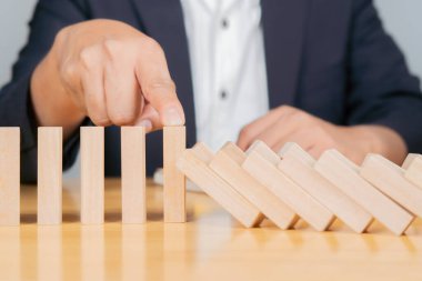 Güvenlik iş geliştirme konsepti. İşadamı eli masaya düşen blokları durdurdu. Yakın çekim, seçici odaklanma.