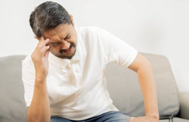 Stresli son sınıf öğrencisi, evde el ele kanepede yalnız oturuyor. Sağlık hizmetleri kavramı.