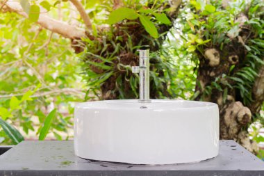 Tropik bir bahçede banyo lavabosu. Açık hava musluğu ve yeşil fıçıya batmak. Bahçedeki tesisler.