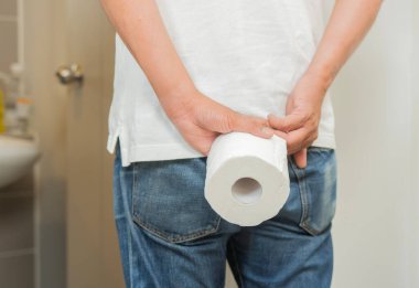 Karın ağrısı ve hemoroit nedeniyle erkek eli poposunu tutuyor. Hemoroit ve kabızlık, sağlık konsepti....
