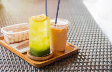 Üzerinde Matcha Green Tea serpiştirilmiş lezzetli tatlı bir yemek taze limon, buzlu kahve ve ahşap kesim tahtasının üzerinde servis edilen biraz kek..
