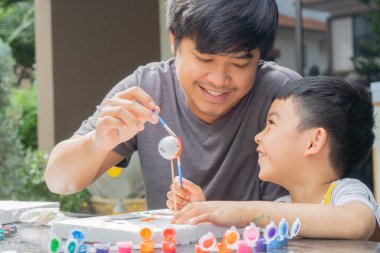 Evde sanat ve zanaat dersinin keyfini çıkarırken, yakışıklı Asyalı çocukla babasının gezegen modeli çizimlerinin yan görüntüsü..