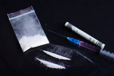 Plastik torbada kokain, kırmızı sıvı uyuşturucu içeren şırınga ve 100 dolarlık banknot, yakın görüş. Uyuşturucu bağımlılığı