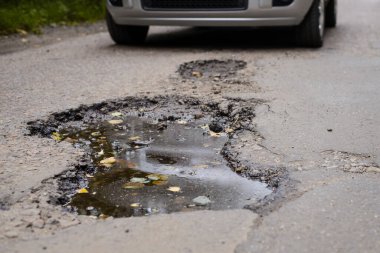 Yol ve otoyol kavramı berbat durumda. Modern gümüş araba, aracın zarar görmemesi için yolun ortasındaki büyük çukurun yanında durdu.