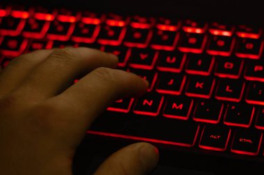 Adamın eli klavyeye kırmızı arka farla yazı yazıyor.