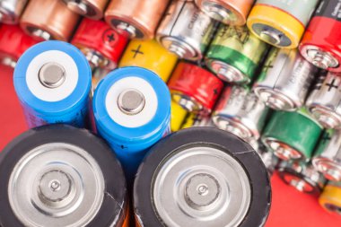 Kırmızı arka planda farklı boyutlarda piller. Gücün sembolü.