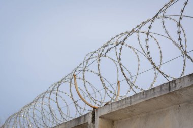 Özel mülkü korumak için duvarın tepesindeki dikenli tellerin fotoğrafı.