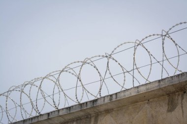 Mavi gökyüzüne karşı koruma duvarının tepesindeki dikenli teller. Avrupa 'daki göçmenlere karşı savaş