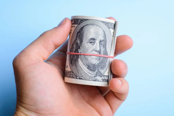 Stock image Hand holding a wad of dollars cash over a blue background