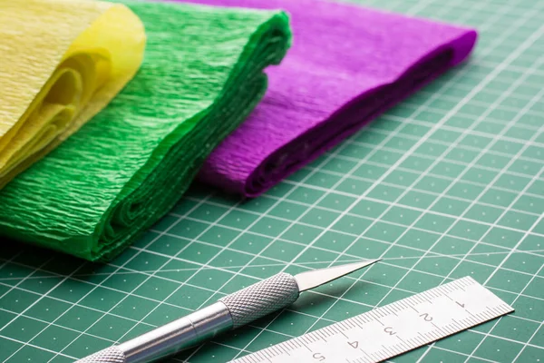 Coloured corrugated papers on cutting mat near scalpel and ruler. DIY origami models at home