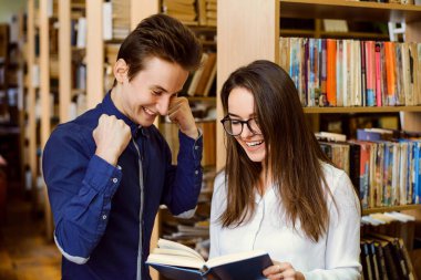 Kitaba bakan gülümseyen erkek ve bayan öğrenciler rapor için gerekli bilgileri bulmaktan mutluluk duyarlar.