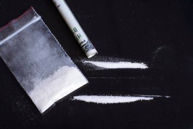 Beyaz toz ilaçlı küçük plastik torba. İki sıra uyuşturucu bağımlısı tarafından solunmaya hazır.