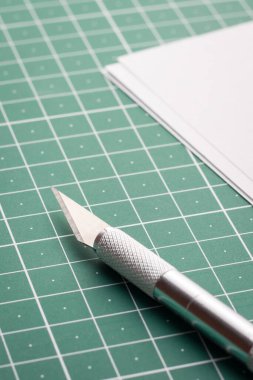 Kağıt bıçağı ve yeşil bir hasırın üzerinde beyaz bir kağıt.