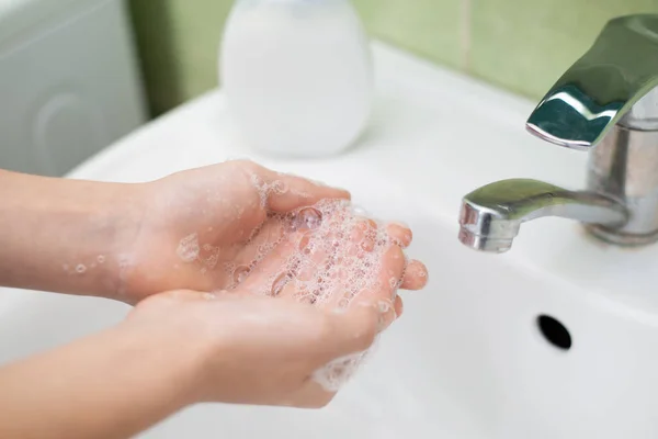 Washing hands with liquid soap at home