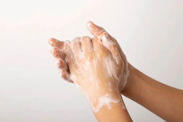 Hands in foam of a small girl while washing them with a soap.