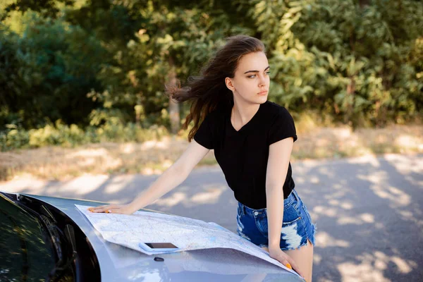若い女性は高速道路で道に迷った 若いドライバーはGpsを持っていないと目的地への道を見つけるために紙の地図を使用します — ストック写真