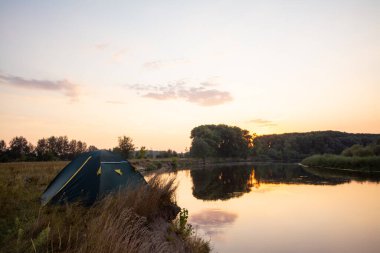 Sabahları nehrin kıyısındaki tenha çadırda. Nehrin kıyısında kamp yapmak.