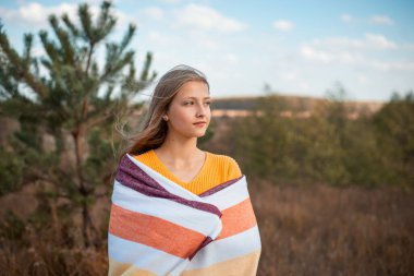 Ekoseli genç bir kızın tarlada dikilirken çekilmiş atmosfer fotoğrafı. Sonbahar, melankolik güzel bir dişinin açık havada çekilmiş fotoğrafı.