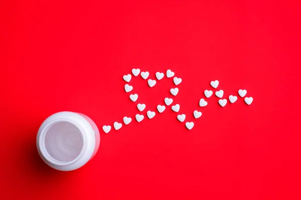 Concept of pills for heart disease. row of pills in shape of heart pulse or beat on red background