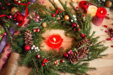 Noel çelengi, ortasında yanan bir mum ve masada süslemeler. Sıcak Noel atmosferi