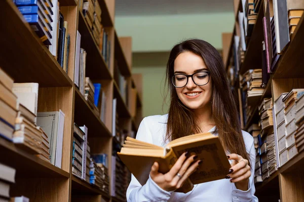 Χαρούμενη Μαθήτρια Κορίτσι Στέκεται Ανάμεσα Στα Ράφια Και Διαβάζει Ένα — Φωτογραφία Αρχείου