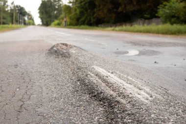 Yüzeyde tümsekler olan berbat koşullarda yol. Bozuk yolun onarılması gerekiyor.