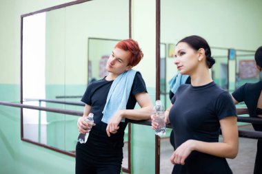 Yorgun dansçılar koreografi dersinden sonra iletişim kuruyor, diğer dansçılara bakıyor, içme suyu içiyor. Zor bir dans dersi.