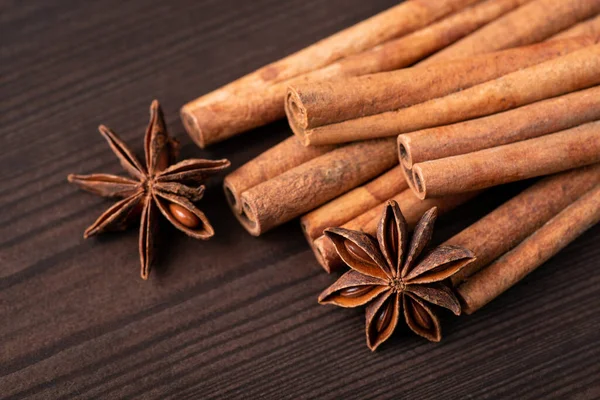 stock image Close-up shot of cinnamon and some stars of anise against black wooden background. Cinnamon and star anise spices