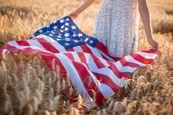 熟したライ麦や小麦にアメリカの国旗を掲げている少女のクローズアップ写真 アメリカ独立記念日 — ストック写真