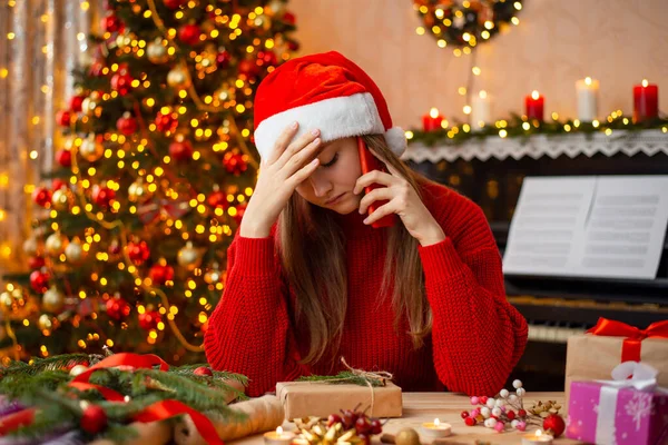 stock image Sad girl talking over the phone, hears bad news. Sorrowful blond girl sitting at the table, preparing presents received terrible news