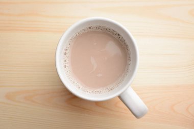 Sütlü bir fincan sıcak kakao ahşap masada duruyor. Sabah içkisi 