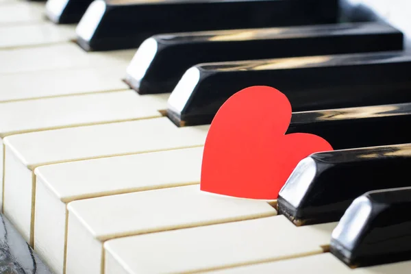 Red heart on a keys of a keyboard of an classic old piano. Concept of love, romantic mood