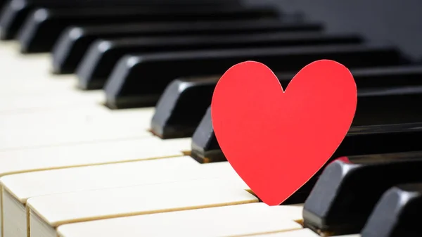 Small red paper heart on piano keys