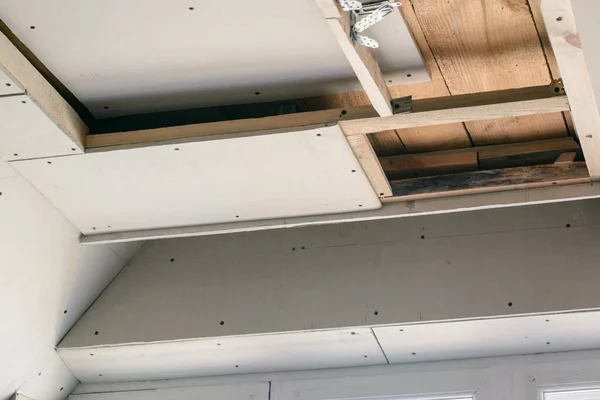 Leaves of the drywall fixed to the wooden frame with screws. Construction walls and suspended ceiling with drywall in a house. Making LED lightning on a ceiling