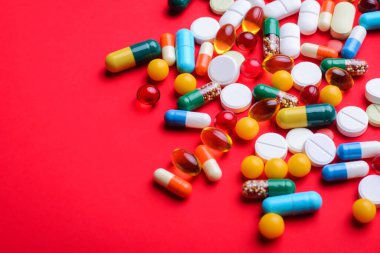 Background of colorful capsules and pills on red background with copy space. Symbol of medicine clipart