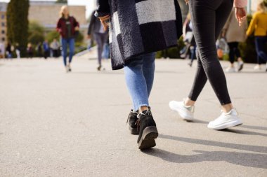 Tatil sırasında üniversitenin yakınında kalabalık bir yer. Derslere ve seminerlere akın eden öğrenciler. İnsanların ayaklarının yakın çekim görüntüsü.