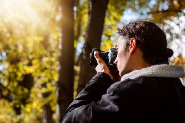 Autumn Park 'ta fotoğraf çeken genç bir adam. Fotoğraf çekimi sonbahar manzaraları
