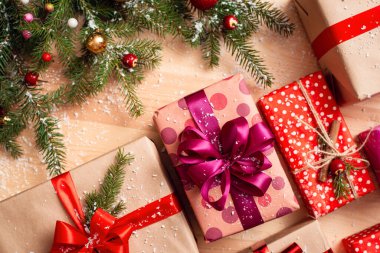 Masanın üzerinde hediyeler olan kutular, parşömen ve kırmızı kağıda sarılmış, sicim ve kurdelelerle süslenmiş. Noel konsepti, sıcak renkler.