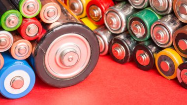 Kırmızı arka planda farklı tip ve boyutlarda bataryalar. Kullanılan alkali piller