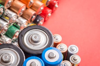 Kırmızı arka planda farklı bataryalar. Geri dönüşümlü doldurulabilir lityum pillerinin sembolü