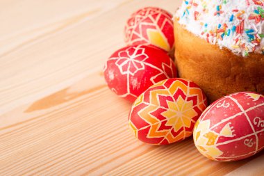 Celebration Easter in Ukraine. Inked eggs near Paska(traditional Easter bread in Ukraine) on light wooden table with copy space